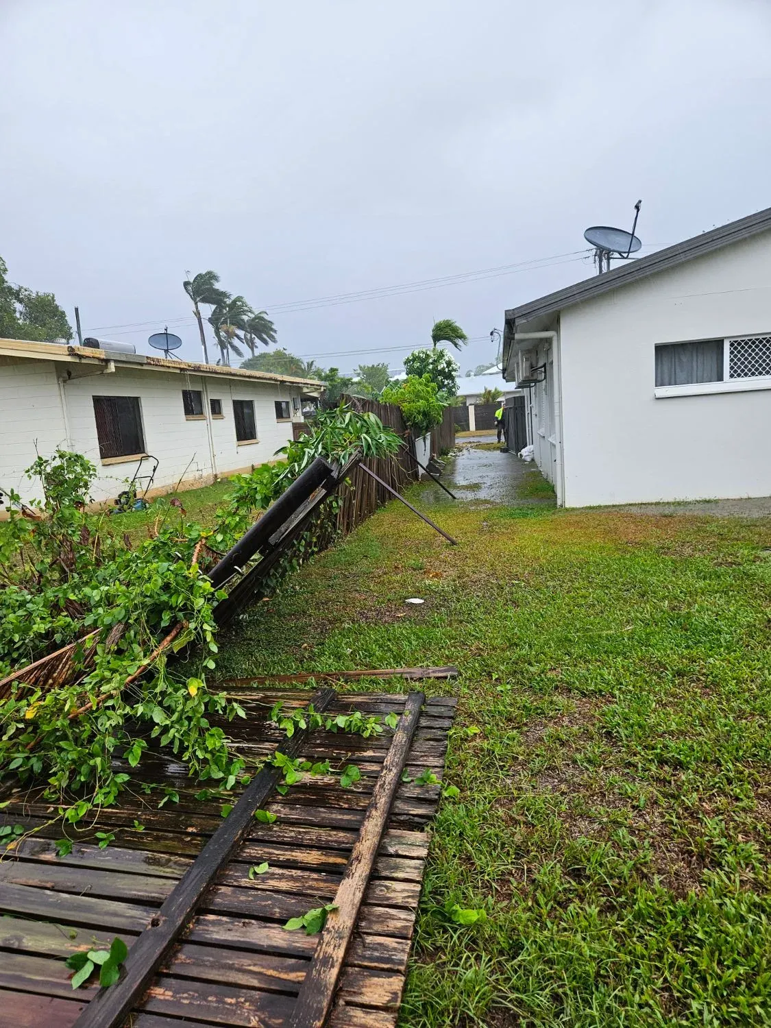 A timber fence blown flat beside a Cairns house after a storm